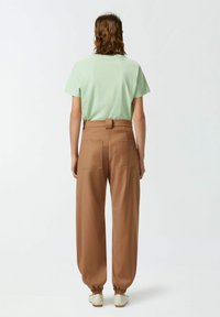 Mint zelena majica kratkih rukava u kombinaciji s smešnim hlačama visokog struka koje imaju stražnje dzepove i elastične manžete. Cipele neutralne boje.