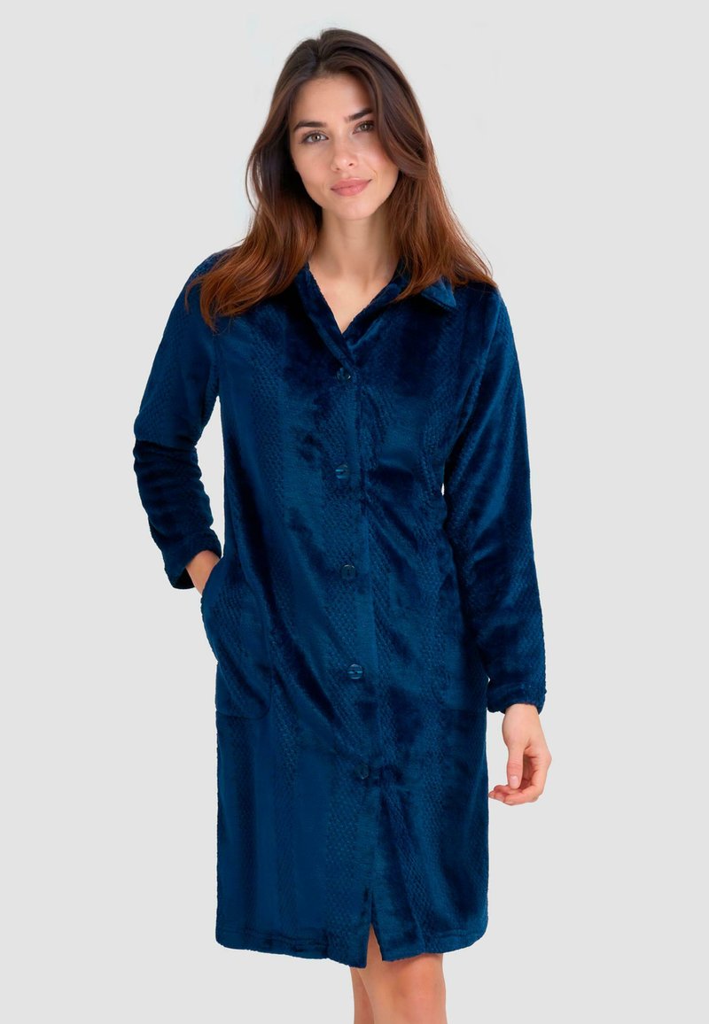 Bata de baño de terciopelo azul marino con cierre de botones, cuello con muesca, mangas largas y patrón texturizado. Presenta bolsillos laterales y un diseño hasta la rodilla.