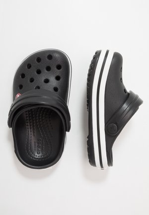 Een paar zwarte Crosstyle instapklompen met ventilatiegaten en een witte gestreepte zool, weergegeven vanuit boven- en zijkant op een witte achtergrond.