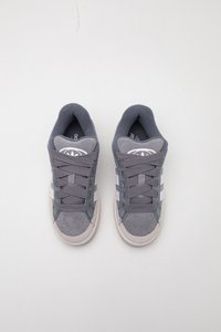 Scarpe da ginnastica grigie con tomaia testurizzata, caratterizzate da accenti grigi chiari e tre strisce bianche, punta arrotondata e lacci piatti.