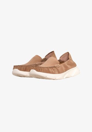 Tan slip-on sko med en blød stofoverdel, dekorativ syning ved tåen og en tekstureret hvid sål til greb og støtte.