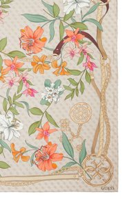 Sciarpa di seta con vivaci motivi floreali in arancione, rosa e bianco su uno sfondo beige chiaro, accentuata da dettagli in oro e catene.