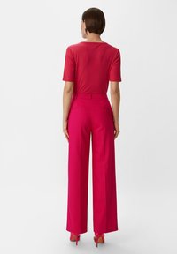 Czerwony prążkowany top z krótkim rękawem połączony z wysokim stanem szerokimi spodniami w intensywnym różu, charakteryzującymi się gładką teksturą i dopasowanym krojem.