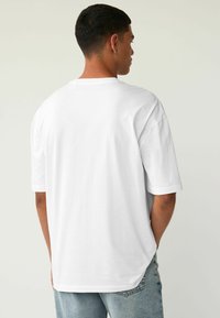 Hvid T-shirt lavet af blød bomuld, med en afslappet pasform, korte ærmer og en rundet kant. Ingen synlige grafikker eller mønstre.