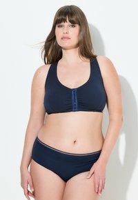 Námořnická modrá podprsenka s předním zavíráním a řasením, doplněná o odpovídající námořnické spodní prádlo s decentním páskem a hladkým povrchem.
