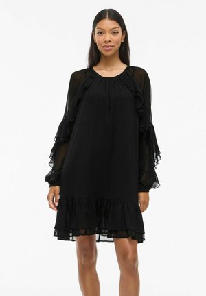 Black dress with ruffled, sheer long sleeves and a ruffled hem. Smooth fabric, loose fit, round neckline, and mid-thigh length.
