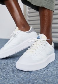 Vita sneakers med en slät läderyta, har rund tå, tonade sömmar och en ljusgrå hälaccent. Mönstrad vit sula.