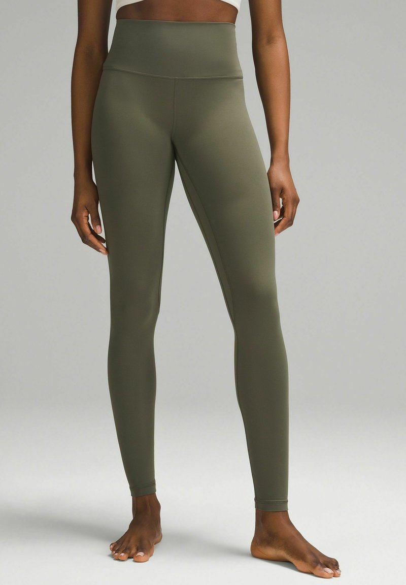 Olivgrüne High-Waist-Leggings aus dehnbarem Stoff, mit glatter Textur und figurbetonter Silhouette, endend an den Knöcheln.