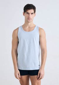 Gaiši zils kokvilnas topiņš ar apaļu kakla izgriezumu, plānām siksniņām un taisnu piegriezumu, ar mazu melnu logotipu apakšmalā.