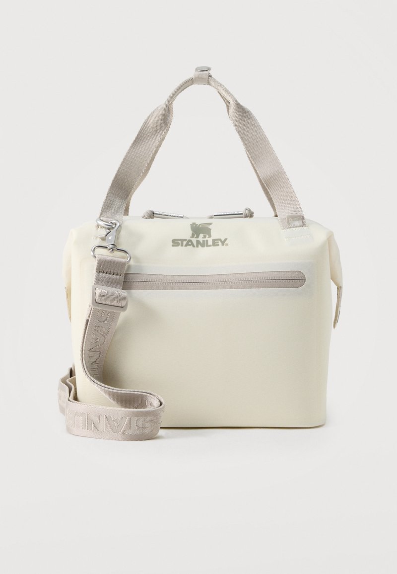 Αυτό το μπεζ μονωμένο τσαντάκι φαγητού Stanley διαθέτει ιμάντα ώμου, μπροστινή τσέπη με φερμουάρ, μαλακές υφασμάτινες λαβές και λογότυπο στο μπροστινό μέρος.