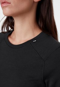 Zwarte sweatshirt met een ronde halslijn, voorzien van een ribbelstructuur en zichtbare stikseldetails. Kleine logotag op de schoudernaad.