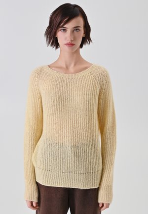 Maglione giallo lavorato a maglia con una vestibilità ampia, texture a costine e scollatura a barca. Le maniche lunghe si restringono ai polsi, mostrando un effetto sfumato.