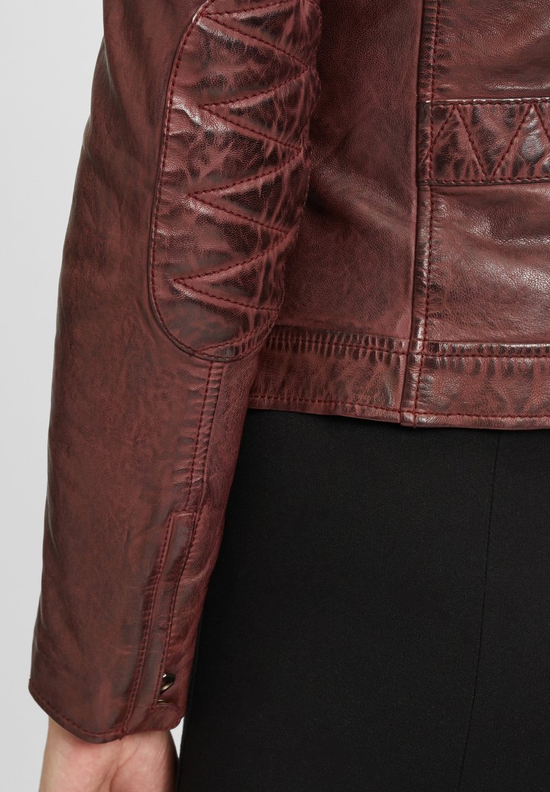 Bordeauxfarbene Lederjacke mit strukturierten Ellbogenpatches, dekorativen Nähten auf den Schultern und taillierter Passform.