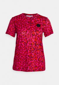 T-shirt à imprimé léopard en rose vif avec des taches noires et rouges. Manches courtes, col rond, tissu doux, avec une petite étiquette logo noire.