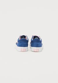 Blå mockasinsneakers med rosa accenter, vita sulor och Vans-logotyp på hälen. Låg sko-design med en enkel, ren estetik.