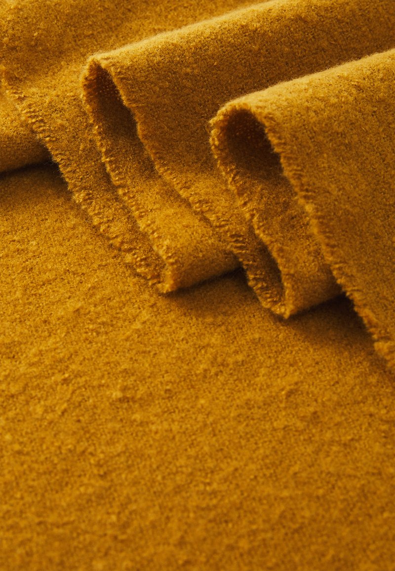 Woolen fabric in a rich mustard yellow, showcasing a soft texture with folded edges and a slight sheen, emphasizing its smooth, warm appearance.