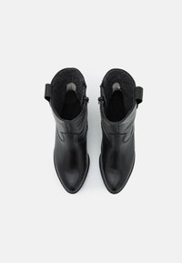 Zwarte leren enkellaarsjes met een spitse neus, een gestructureerde grijze binnenvoering, zijritsen en een geweven treklus achteraan.