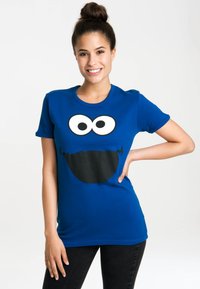 Blue cotton T-shirt featuring a large black-and-white graphic of a smiling character's face, short sleeves, and a rounded neck.