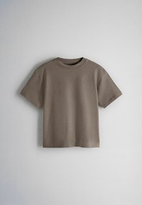 Egyszerű, rövid ujjú taupe színű póló kerek nyakkivágással, világosszürke háttéren kiállítva.