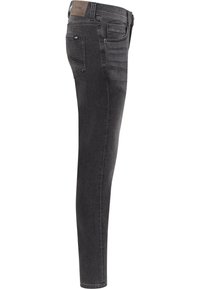 Jean slim noir délavé, montré de profil avec poches avant et arrière visibles et un patch en cuir marron à la ceinture.