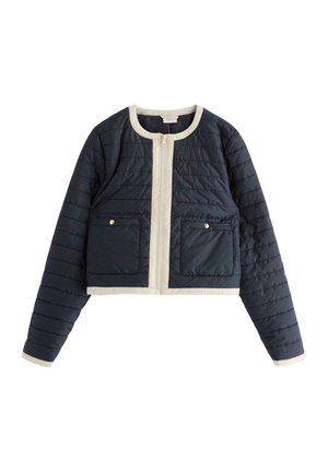 Navy quilted cropped jacket with cream accents, featuring a rounded neckline, front zipper, and two patch pockets with gold buttons.