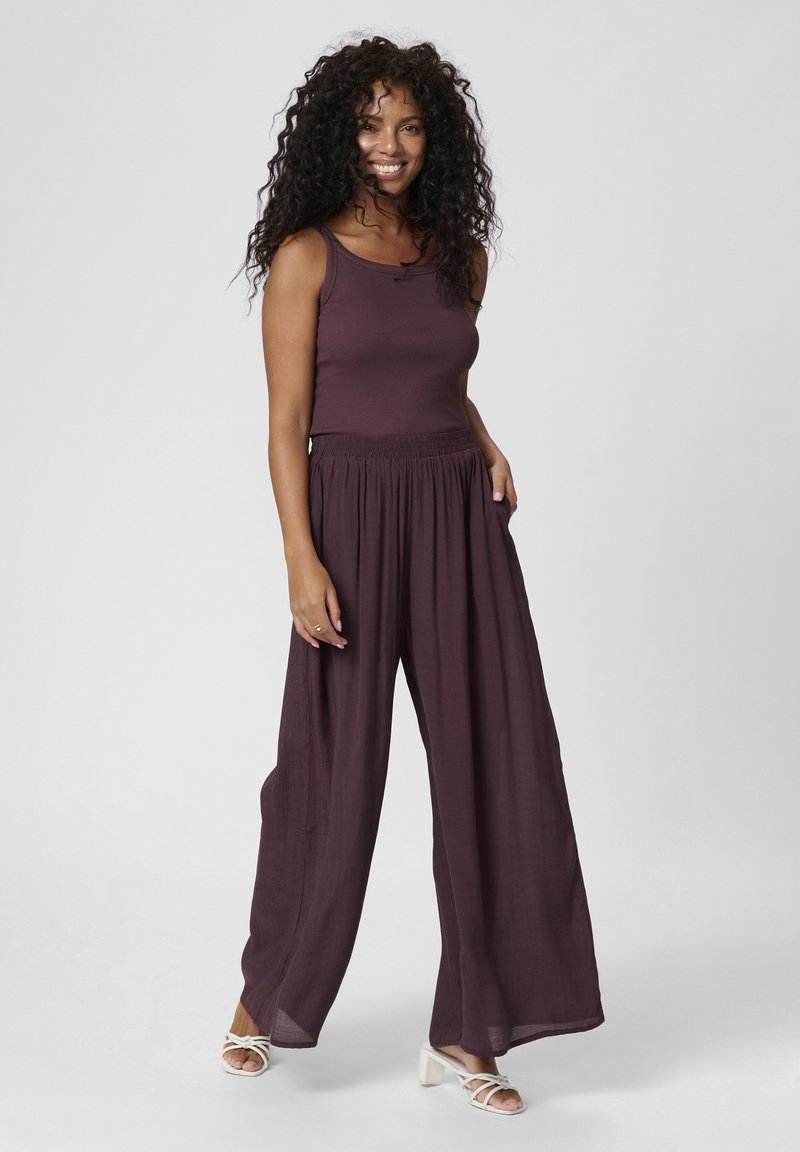 Pantaloni a gamba larga bordeaux con una vestibilità ampia e una vita elastica, abbinati a un top aderente coordinato. Tessuto testurizzato e leggero.