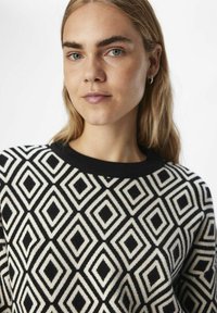 Must-valge nööbitekk, millel on teemantmuster ja ümmargune kaelus. Pehme tekstuur kontrastsete mustade soonikservadega.