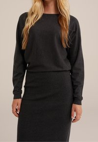Conjunto de dos piezas en gris oscuro que incluye una blusa de manga larga con escote barco y una falda de punto hasta la rodilla, confeccionada en una tela suave.