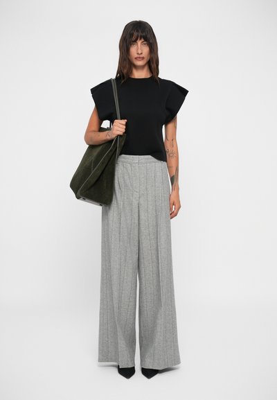 Top negru cu mânecă scurtă, cu design structurat al umerilor, pantaloni evazați gri plisati și o geantă de mână verde închis. Detalii din țesătură texturată prezente.