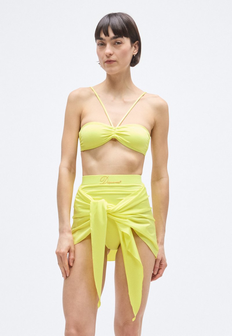 Élénk sárga bikini rakott bandeau felsőrésszel, vékony pántokkal és magasderekú alsó résszel, amely megkötős övrésszel rendelkezik. Simább, rugalmas anyag.