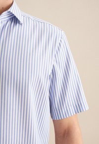 Camicia a maniche corte realizzata in tessuto leggero, caratterizzata da righe verticali blu e bianche, con colletto classico e texture liscia.