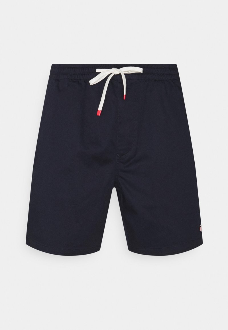 Shorts de bain bleu marine avec une taille élastique et un cordon blanc, avec des accents rouges. Tissu lisse, longueur mi-cuisse, design simple.
