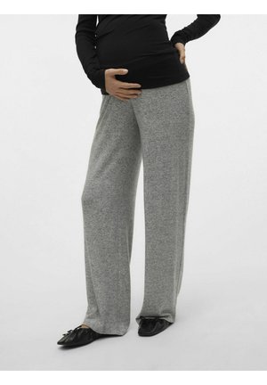 Pantaloni larghi in tessuto jersey grigio, con un taglio rilassato, dotati di una cintura elastica, abbinati a scarpe nere morbide e piatte.