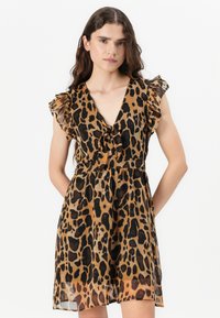 Leopard print dress in sheer fabric, featuring a deep V-neck, ruffle sleeves, and a gathered waist, with a flowing silhouette.