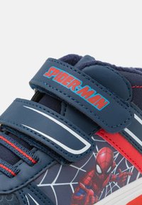 Blue and red sneakers with Spider-Man graphic, featuring a Velcro strap, synthetic materials, and a textured sole.