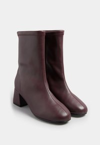 Bordowe skórzane botki za kostkę na słupku, smukły design, przeszywane detale i gładka tekstura.