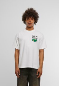 Hvid bomulds T-shirt med korte ærmer, der har teksten "Call My Lawyer" og et grafisk billede af penge. Afslappet pasform med rund halsudskæring.