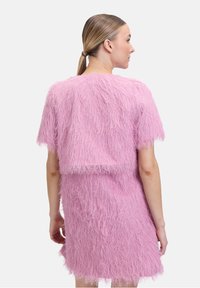 Rosa strukturiertes Zweiteiler-Outfit mit einem flauschigen, zotteligen Design; kurze Ärmel und runder Ausschnitt. Das untere Teil ist ein knielanges Kleid.