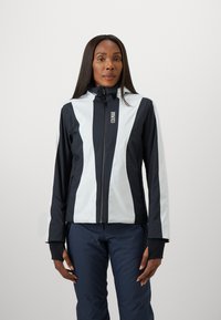 Schwarze und weiße Jacke mit hohem Kragen, Reißverschluss vorne und Daumengriffen. Glattes, wasserabweisendes Material mit kontrastierenden vertikalen Streifen.