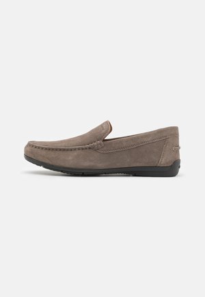 Mocasines de ante gris con una textura suave, punta redonda y detalles de costura a lo largo de la parte superior. Suela de goma para mayor agarre y flexibilidad.