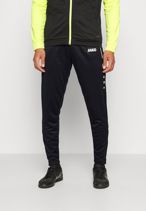 Pantalons de sport noirs en mélange de polyester, avec une coupe fuselée, logo JAKO sur le devant et trois boutons blancs le long du côté.