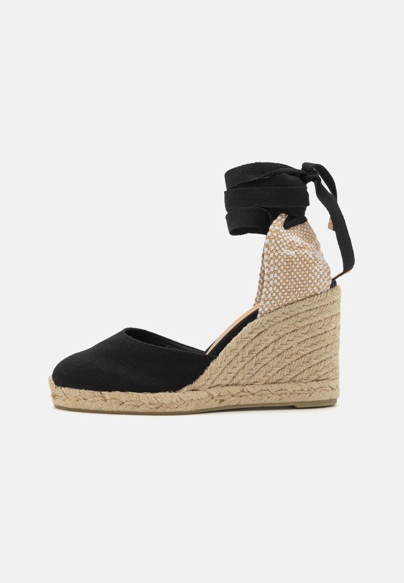 Espadrilha em lona preta com salto em corda trançada, tiras para o tornozelo e um detalhe de salto texturizado em bege.