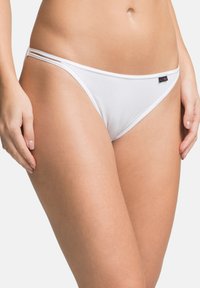 Slip bikini bianco in cotone con doppie fascette laterali, design a vita bassa e un piccolo tag decorativo sulla vita.