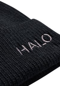 Schwarze gestrickte Mütze mit einem strukturierten Muster, das ein hellrosa gesticktes Logo trägt, auf dem "HALO" steht. Der Rand der Mütze ist umgeschlagen.