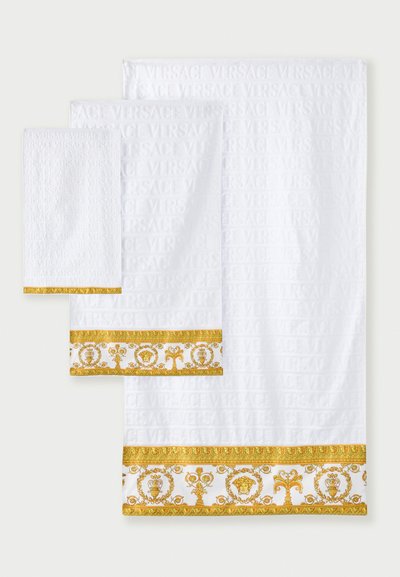 Ensemble de trois serviettes blanches avec le texte en relief "VERSACE", ornées d'une bordure à motifs dorés et blancs. Texture douce et tailles variées.