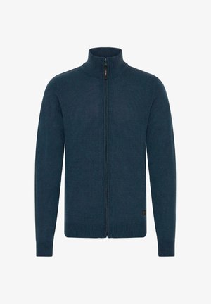 Pletený zipový sveter tmavomodrej farby s vyšším golierom, rebrovanými manžetami a rovnou spodnou časťou. Hladká textúra so subtílnym vzorom.