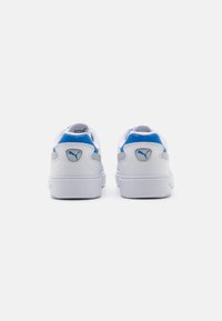 White sneakers with blue and gray accents, featuring a smooth leather upper, round toe, and textured sole. Logo on the heel and tongue.