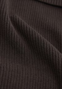 Brauner, gerippter Stoff mit weicher Textur, der vertikale Linien und ein glattes Finish aufweist, geeignet für Kleidungsstücke und Accessoires.