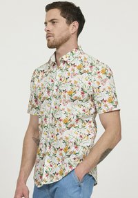 Korte mouwen bloemenshirt met een witte achtergrond, met levendige kleurrijke bloemen en vlinders, een knoopsluiting en een kraag.