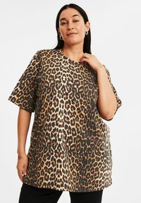 Leopardmönstrad T-shirt, kortärmad, rund halsringning, lös passform, gjord av mjukt tyg med svarta, bruna och tanfärgade mönster.